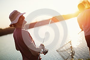 Men fishing in sunset and relaxing while enjoying hobby