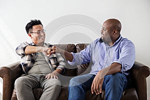 Men fist bumping celebrating on couch photo