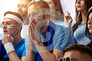 Men, football fans emotionally watching match with worrying faces, supporting soccer team of greece during tense game