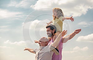 Men generation: grandfather father and grandson playing with raising hands or open arms outdoor on sky. Boy dreams of