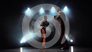 Men with a girl preparing for a kickboxing competition. Light from behind. Smoke background. Slow motion