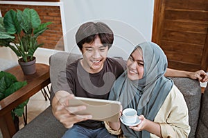 Men and girls in hijab look at the smart phone screen while taking selfies while smiling