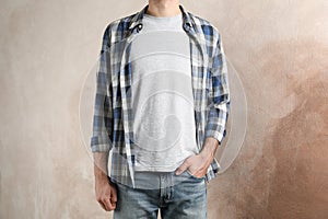Men in grey t-shirt and checkered shirt against brown background