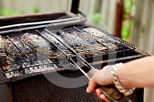 Men grilling fish mackerel on barbecue cooked on the grill in the open air flow, tasty and fresh food, picnic, party,