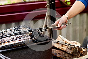 Men grilling fish mackerel on barbecue cooked on the grill in the open air flow, tasty and fresh food, picnic, party, outdoor recr