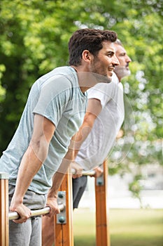 men in gym doing pull-ups on horizontal bar