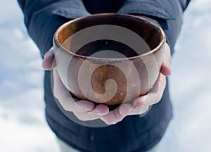 Men hand holding empty wooden bowl