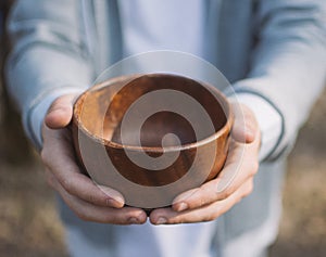 Men hand holding empty wooden bowl