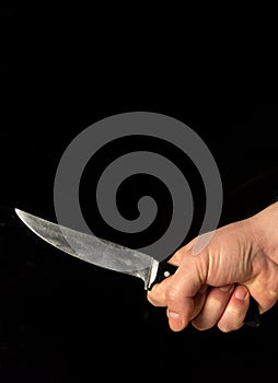 Men hand holds sharp knife isolated against black background