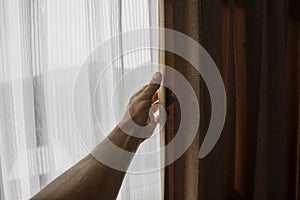 Men hand opening curtain in bed room.