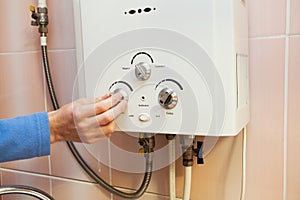 Men hand regulate the power of hot water in Gas water heater.