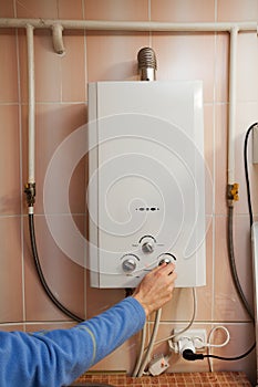 Men hand regulate the temperature of hot water in Gas water heater.