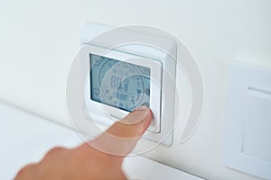 Men hand setting temperature on the underfloor heating control panel