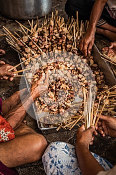 Men hands preparing a balinese traditional sate for cooking. Bali island.