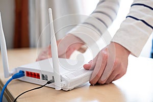 Men hands set up and install broadband high speed internet Wifi router on working table at home. With blue fiber connection line.