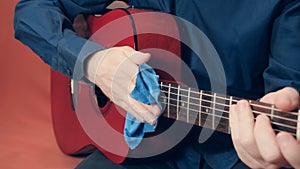 Men hands take care of acoustic guitar wiping tool from dust photo