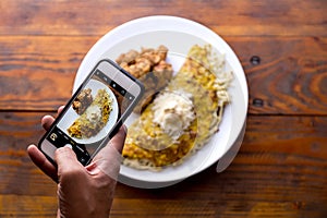 Men hands taking food photo of VENEZUELAN CACHAPA by mobile phone