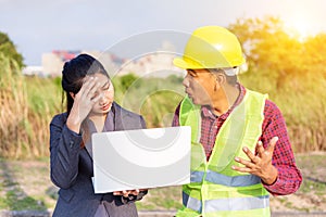 Men in hard hats and uniform with young woman. Team of architects, engineers discussing work. A women hold laptop