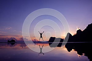 Men are having fun jumping in the morning at sunrise on the beach, reflections on the water surface