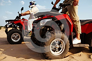 Men in helmets and glasses ride on atv in desert