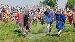 Men in historical costumes, in knight`s armor pass by the audience at the festival of the middle ages