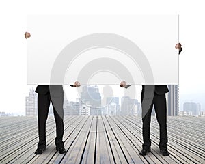 Men holding board standing on wooden floor