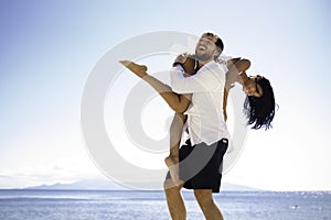 Men holding his wife passionately, sitting in the water, sunny day in summer time,  on a seascape background.