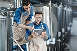 Men inspectors with digital tablet technician inspecting modern beer factory plant