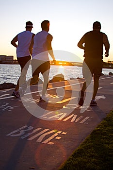 Men jogging at the beach at sunset