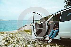 men legs stick out from car parked at sea beach