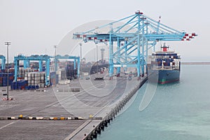 Men load cargo boat docked to industrial port photo
