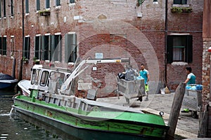 Men loading trash on garbage boat, Venice