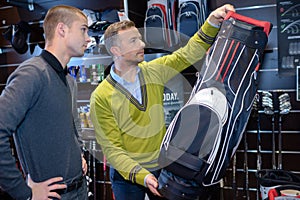 Men looking at golf club bag in sports shop