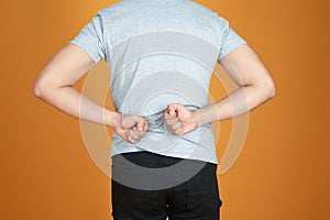 Men with low back pain on a color orange background / medical and health concepts