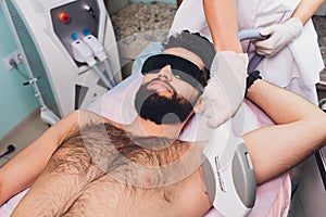 Men lying at beautician& x27;s during laser armpit hair removal therapy.