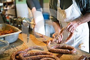 Men making sausages the traditional way using sausage filler.