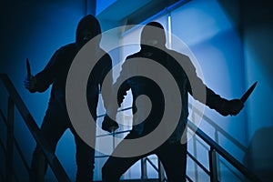 Men in masks with knives on stairs. Dangerous criminals photo