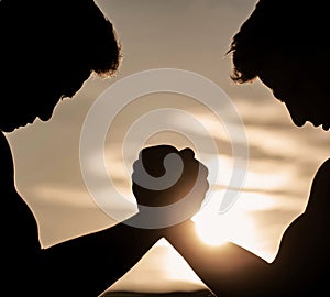 Men measuring forces, arms Two men arm wrestling. Rivalry, vs, challenge, hand wrestling. Sunset, sunrise. Rivalry