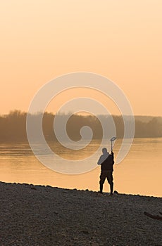 Men with metal detector in sunset