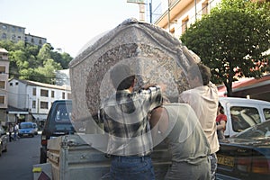 Men moving couch in Ainsa, Huesca, Spain in Pyrenees Mountains