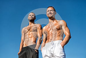 Men muscular bare torso stand outdoor. Men muscular body posing confidently with hands in pockets. Sportsmen