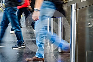 Men passing through stainless steel ticket gates with motion blur