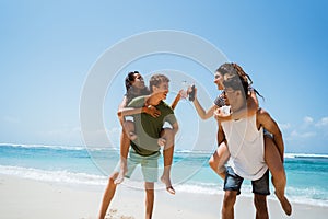 Men piggybacking women holding softdrink bottle