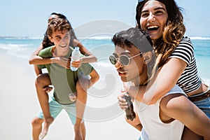 Men piggybacking women holding softdrink bottle