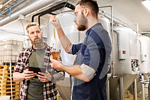 Men with pipette testing craft beer at brewery