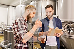 Men with pipette testing craft beer at brewery