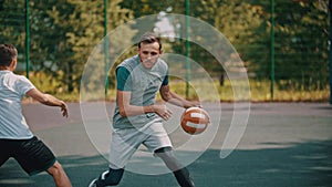 Men playing basketball on the sports ground outdoors - a man dribbling avoiding his opponent