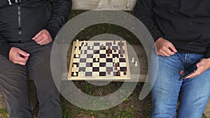 Men playing chess in park on bench