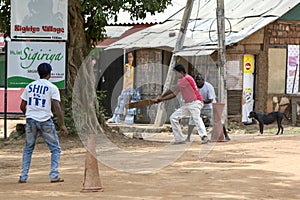 Men playing cricket on a dirt pitch in the street at Sigiriya, Sri Lanka.