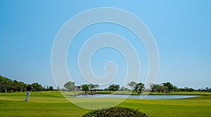 Men playing golf in the middle of the golf course ,Landscape golf course and blud sky